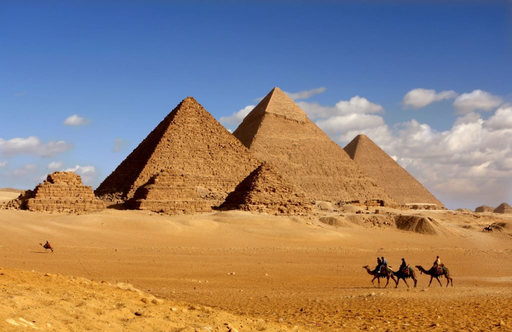 Camel back riders in front of pyramids in Cairo Egypt