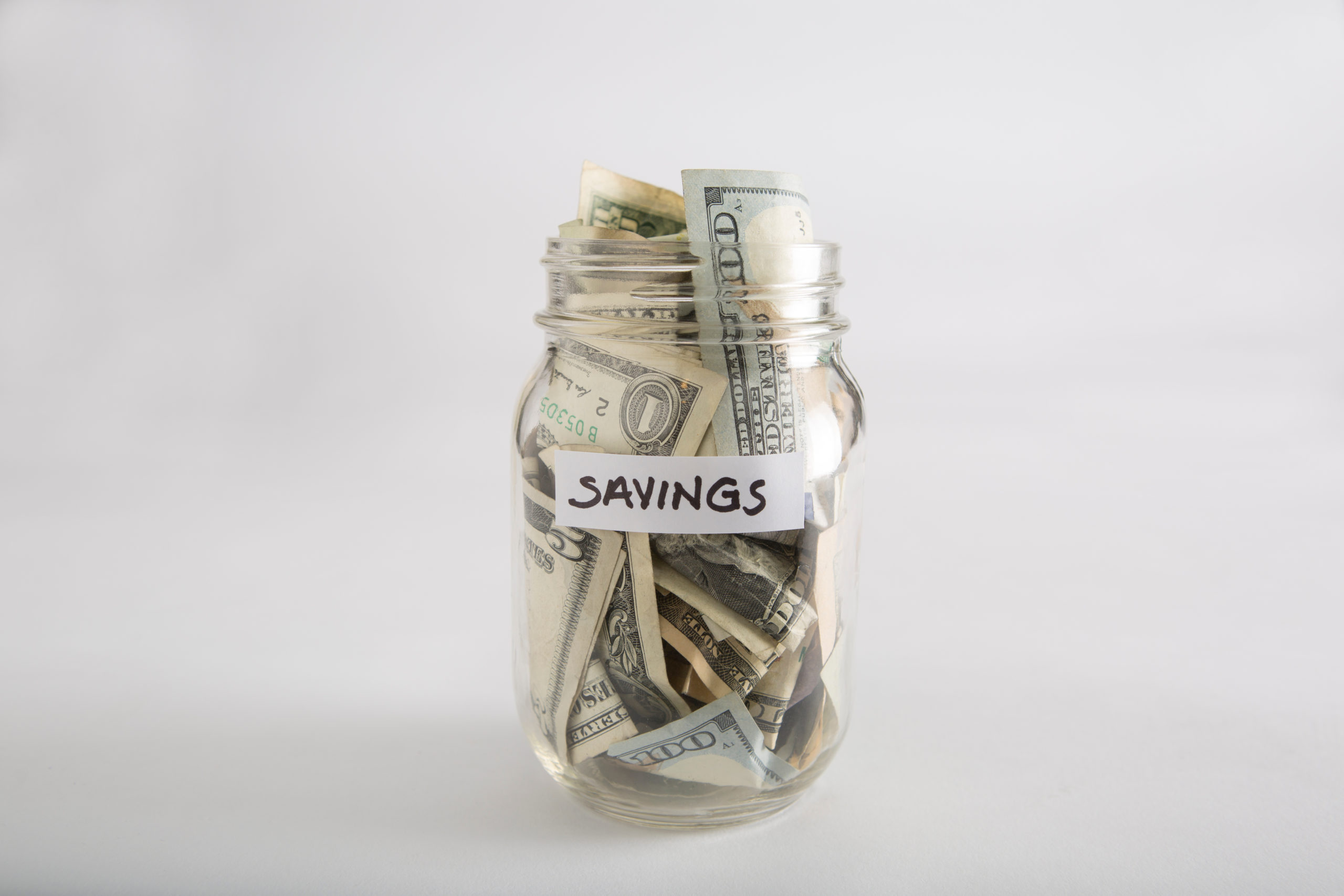 a mason jar full of money labeled savings that someone wants to use to travel and book travel agents.