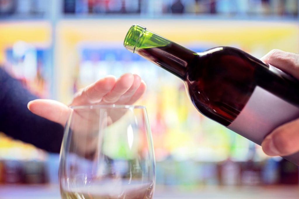 a woman traveling to Brazil with Jaya stops the waiter from pouring more wine to not overindulge and offend people with bad etiquette.