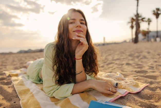 A woman on tour with Jaya Travel & Tours is sitting on the beach in a cover up to be respectful and follow etiquette.