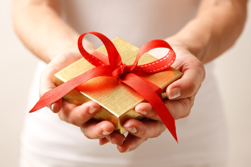 A woman holds a small gift of gratitude for their host during their South Africa travel tour because it is proper etiquette to present a gift.