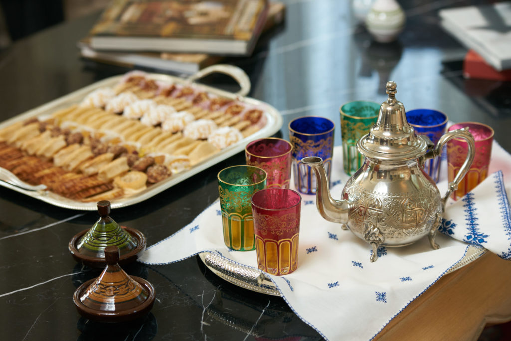 A tray of Egyptian tea sits on a table in front of colorful glasses and a tray of traditional cookies for celebrating the traditional arabic tea culture with Jaya Travel and Tours in Egypt.