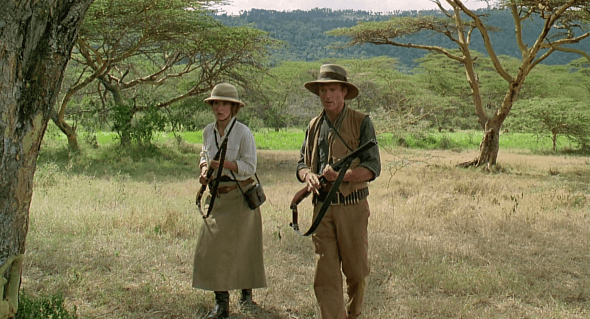 Karen Blixen, played by Meryl Streep, and Denys Finch Hatton, played by Robert Redford, hold guns and walk through the forest on alert in the movie Out of Africa.