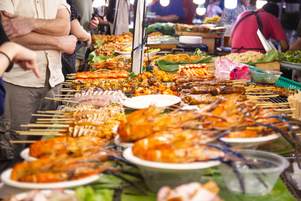 In a weekend market a stall sells bbq seafood grilled on sticks to the customers in the night market in Bangkok, Thailand.