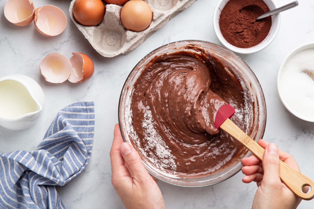 A woman in the kitchen mixes a bowl of chocolate cake mix to bake a yummy snack food on culinary tours with Jaya.