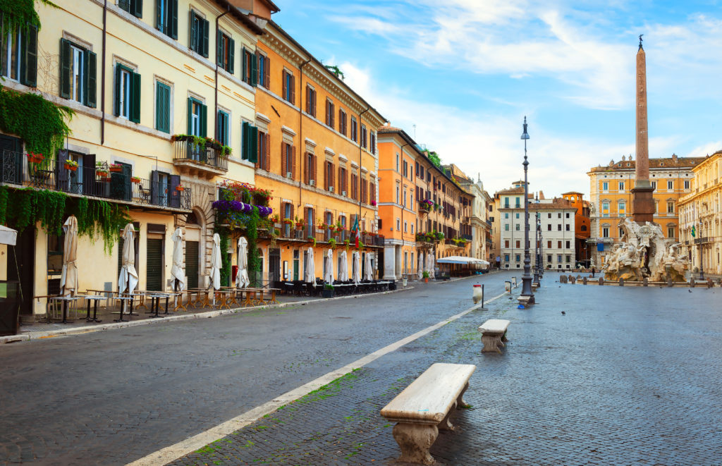 a far view of the piazza navona in rome italy with pastel colored buildings and the trevoli fountain which was an important movie location for the film eat pray love.