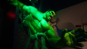 The gigantic hulk crashes through a wall at a marvel disney avengers ride.