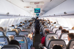 the inside of an airplane cabin with travelers sitting in the window seats and aisle seats and the stewardess.