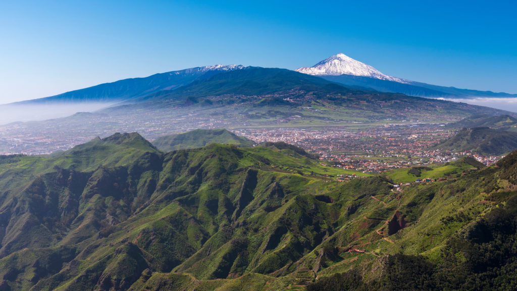 A scenic view of Mount Teide, an active volcano in Spain’s Canary Islands in the Teide National Park, hiding behind a mountain with lava and magma on the inside.