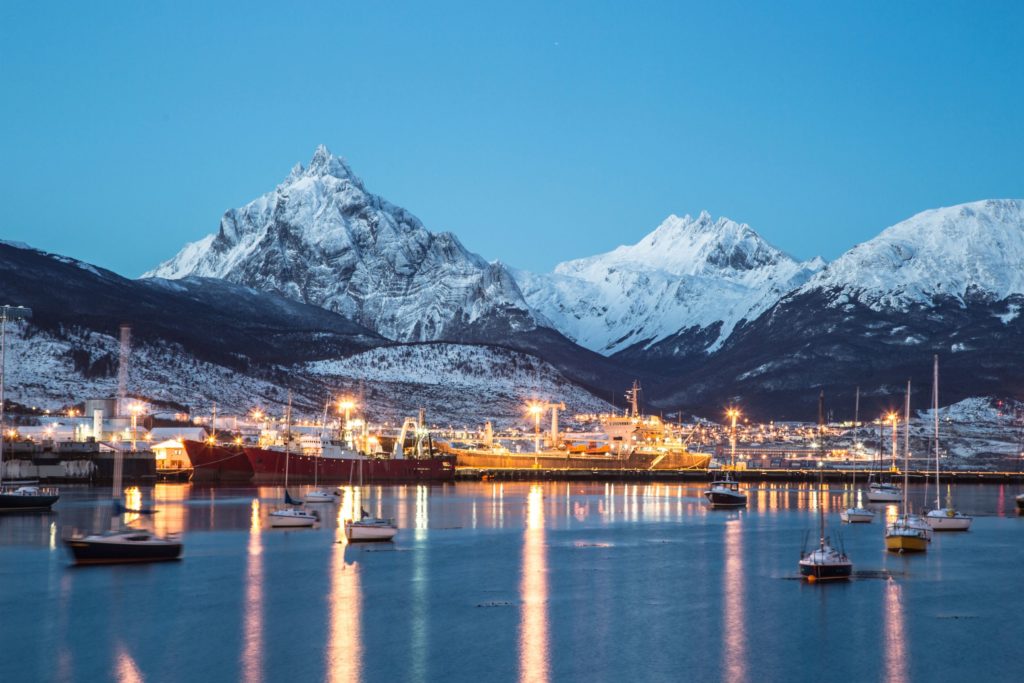 The town of ushuaia, in Patagonia, Chile, lit up at night with the tierra del fuego patagonian mountains in the background.