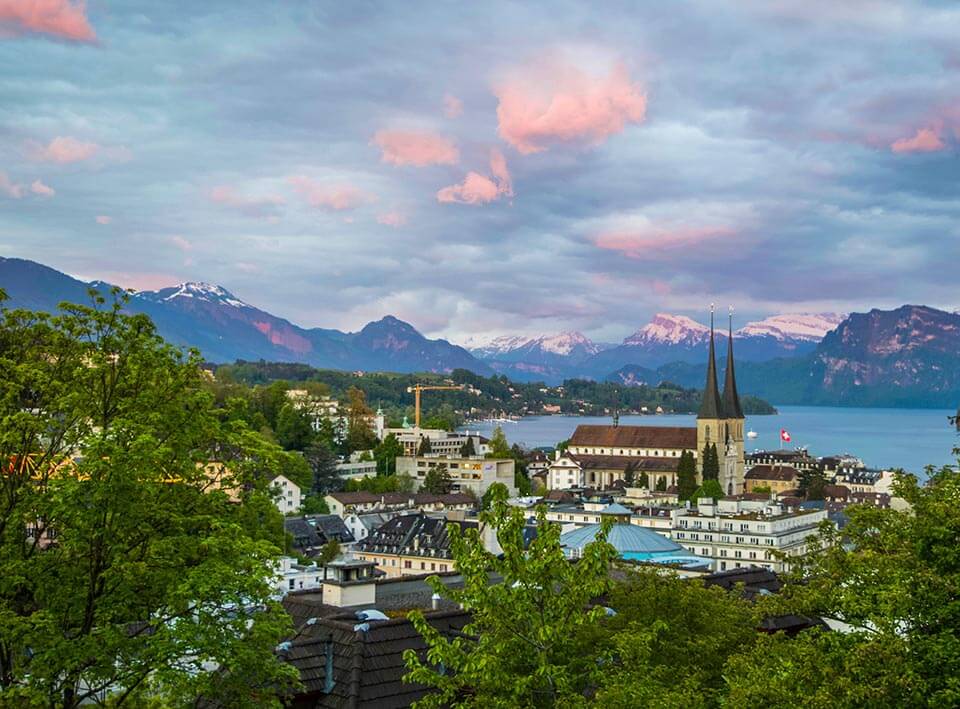 An aerial view the architecture of Lucerne, Switzerland with snowcapped mountains in the distance on this Valentine's Day Honeymoon destination with Jaya Travel & Tours.