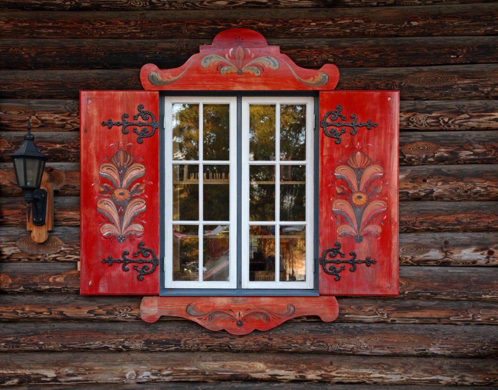 A traditional nordic village house with a red and white painted window. Jaya Travel & Tours gets clients to Tomteland, Sweden which celebrates the mayfestival with these colors during midsummer.