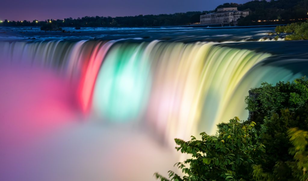 A beautiful photo of the waterfall in America, Niagara Falls, with colorful lights highlighting the waterfalls. This is an image from Jaya Travel & Tours blog "Which Waterfall Should You Visit Quiz?"