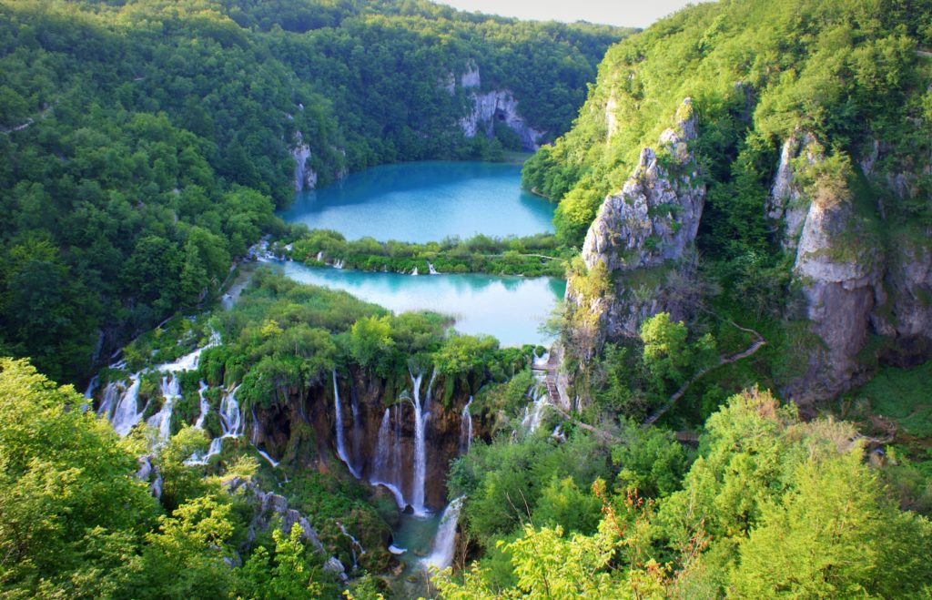 The beautiful Plitvice Waterfalls in Croatia at the Plitvice Lakes National Park. The bright blue water and vibrant green trees are featured in Jaya Travel & Tours blog article called "Which Waterfall Should You Visit Quiz?"