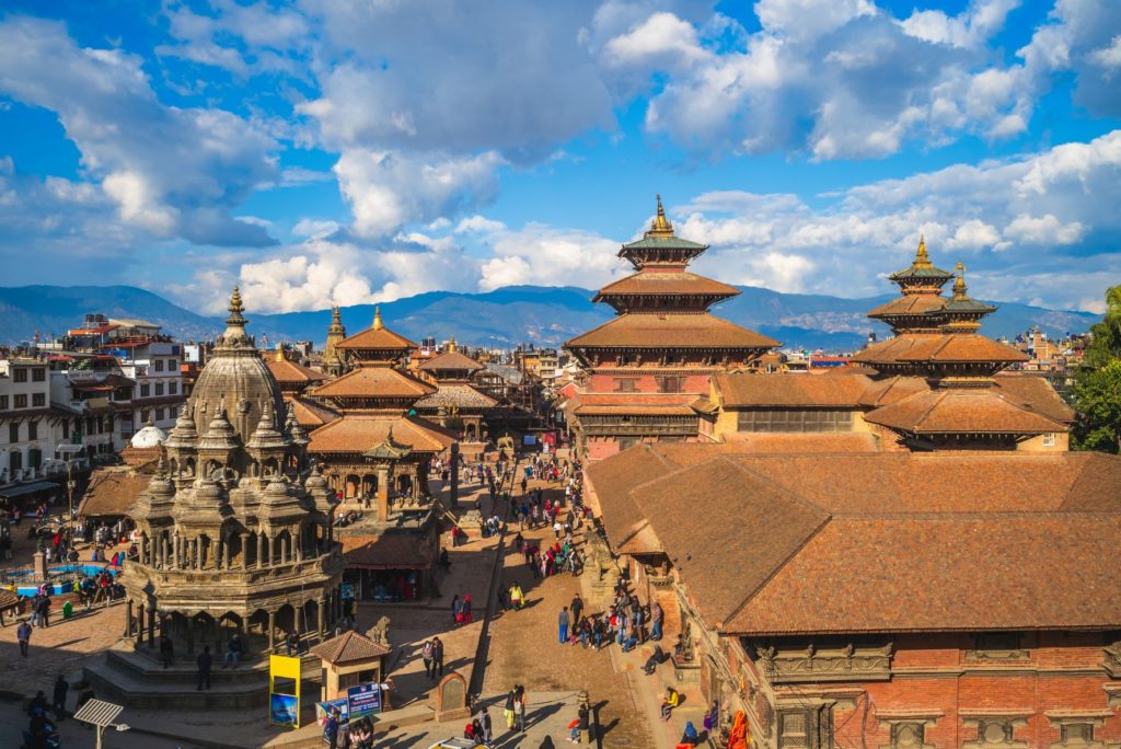 Jaya Travel features an image containing: A small market called Durbar Square in Kathmandu, Nepal with ancient red-stone temples and buildings that people love to tour on vacation to Nepal, a great vacation destination for travel.