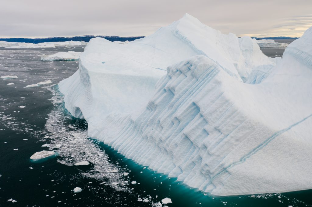 A giant chunk of ice broken off from a glacier floats in the dark arctic sea close to the infamous Greenland Ice Sheet. This image is featured in the Jaya Travel & Tours blog, "Which Glacier Should You Visit Quiz," which is a personality travel quiz that determine your next glacier tour.