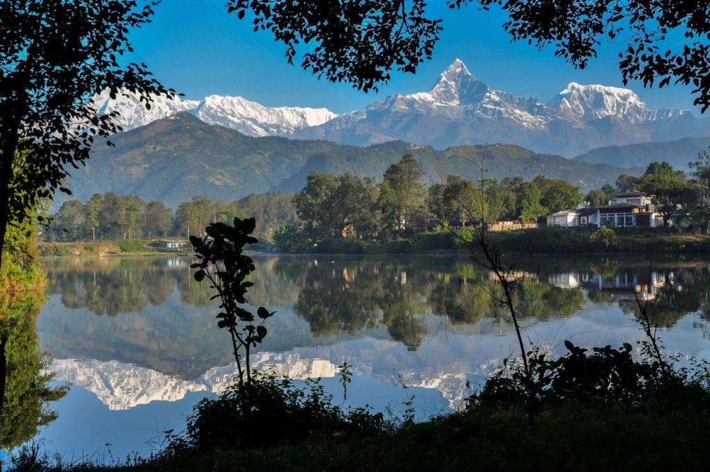 Jaya Travel & Tours features an image of Pokhara in the Gandaki Province of Nepal on their travel blog for the article about the top 10 destinations of 2023. In the image, there is a mountain in the background and a lake reflecting that image upside-down.