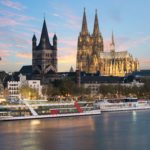 The cityscape of Cologne, Germany with a high-end cruise ship for customized vacation plans such as The beautiful Danube River Cruise by Crosi. This image is featured on the Jaya Travel & Tours cruise booking page, which lists the current river cruises and ocean cruises offered.