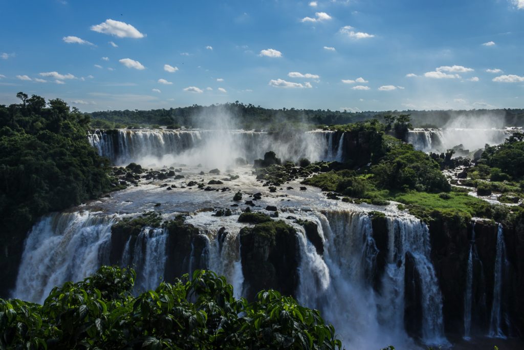 A landscape shot of the Iguazu Waterfalls in Brazil with multiple levels of waterfalls cascading down into eachother. This image is featured in the Jaya Travel & Tours blog post, "On Location: Black panther & Wakanda Forever," which lists the filming destinations of the popular marvel movie series.