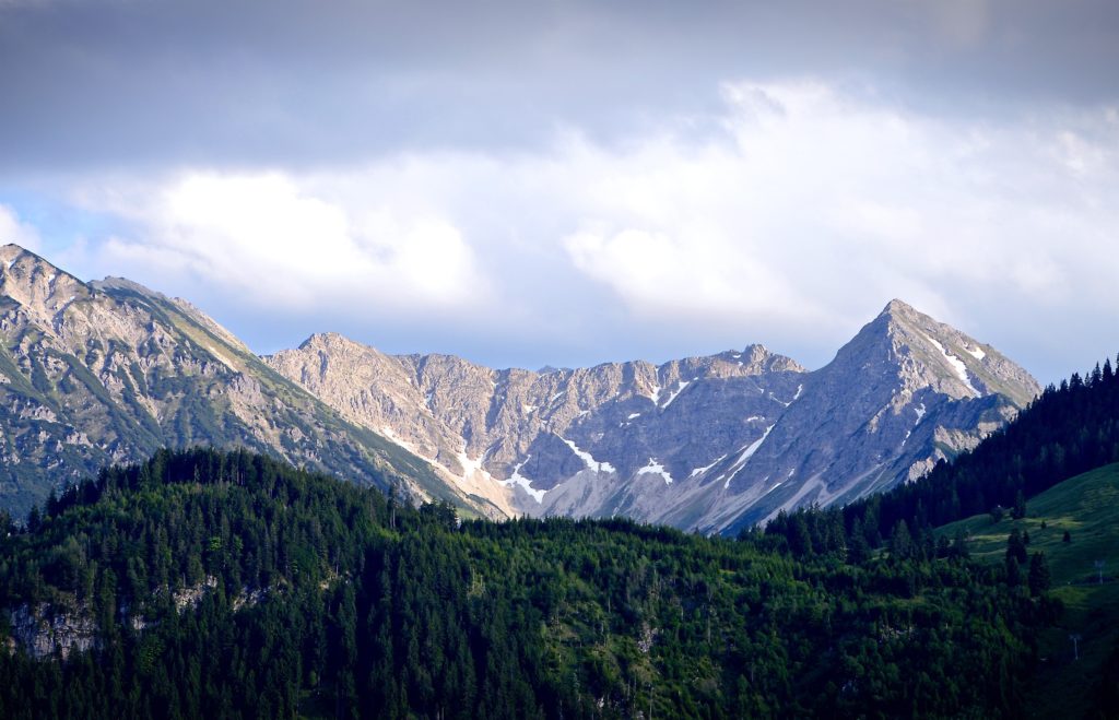 This photo of a mountain range and forest is the featured image in the Jaya Travel & Tours blog post "Germany Travel Guide" which shares everything traveler needs to know about the German vacation destination.