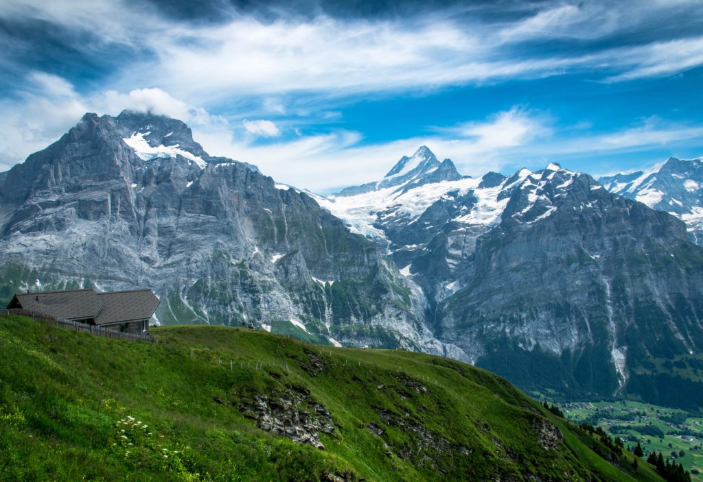 This image of the Swiss alps and a cabin build onto a cliff is featured in the Jaya Travel & Tours blog post "Switzerland Travel Guide"