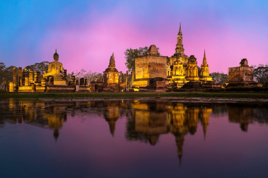This image of the city of bangkok lit up at night with a purple sunset is featured in the Jaya Travel & Tours blog post "Thailand Travel Guide"