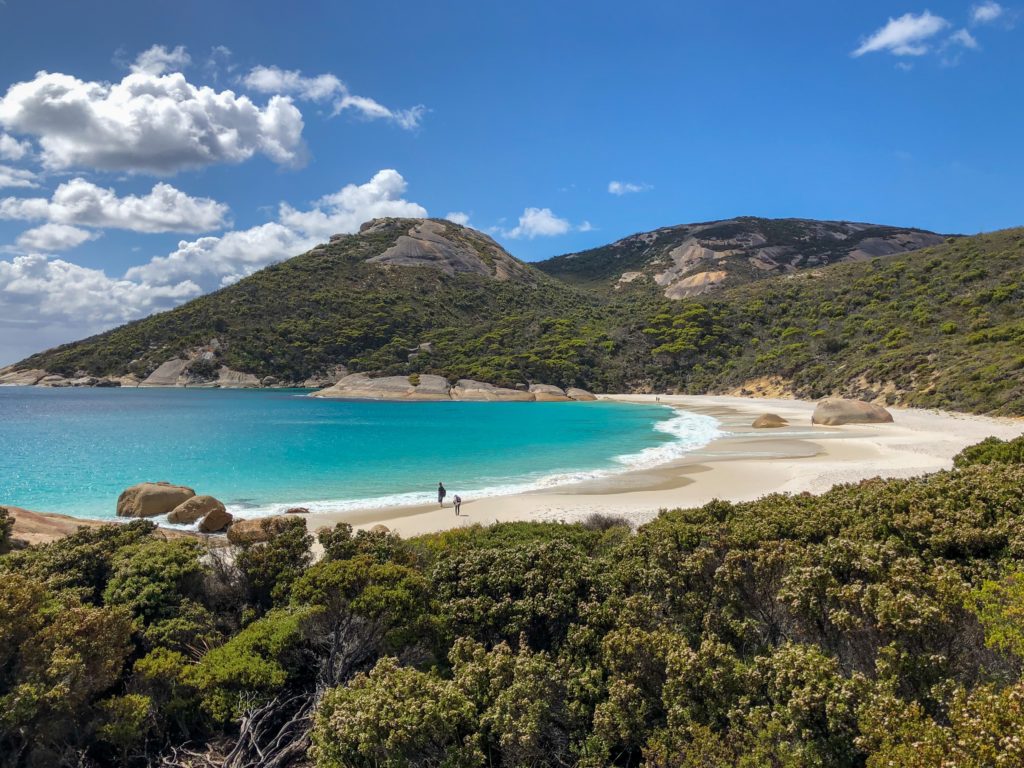 This image of a beautiful inlet bay with bright blue water surrounded by a lush forest and is featured in the Jaya Travel & Tours blog post "Australia Travel Guide"