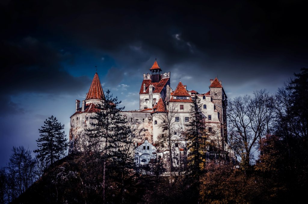 This image featured in "Celebrate Halloween Around the World" from Jaya Travel & Tours features the Bran Castle, or Dracula's Castle, in Transylvania which is on a hill surrounded by spooky forest.