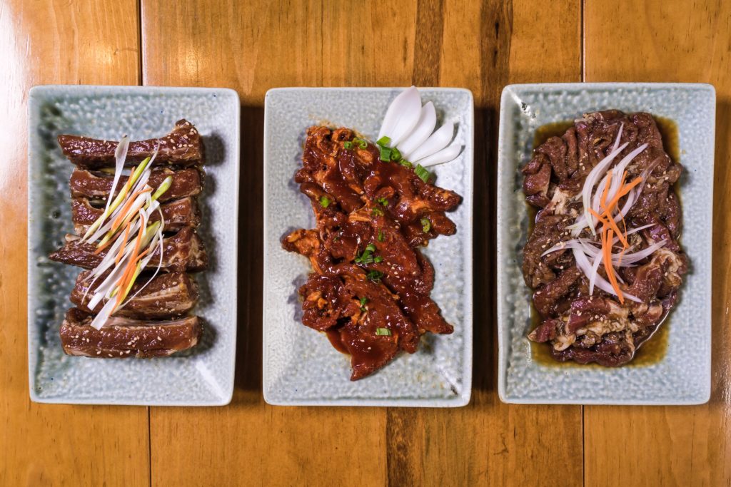 Featured in Korean Cuisine by Jaya Travel & Tours, this image shows three plates of yummy food from Korea including ribs called galbi.