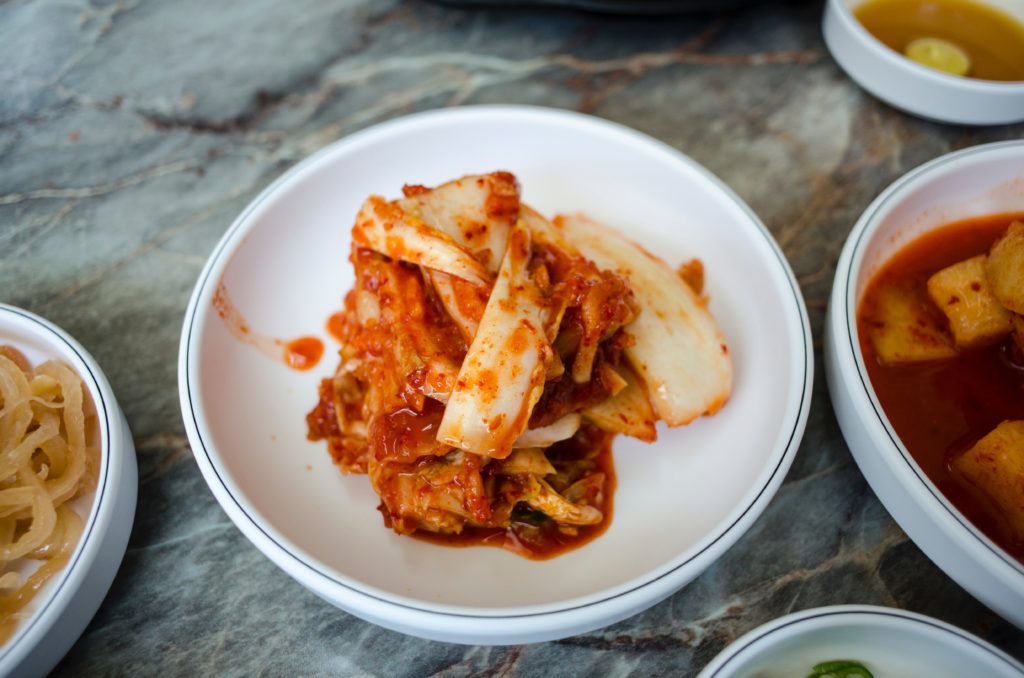 Featured in Korean Cuisine by Jaya Travel & Tours, this image shows a pile of Kimchi on a plate - which is a delicacy in Korea.