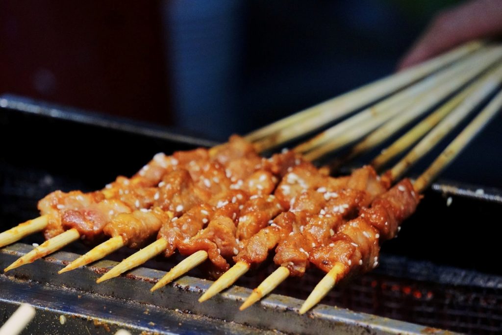 Featured in Korean Cuisine by Jaya Travel & Tours, this image shows skewers of meet on a street market bbq in korea.
