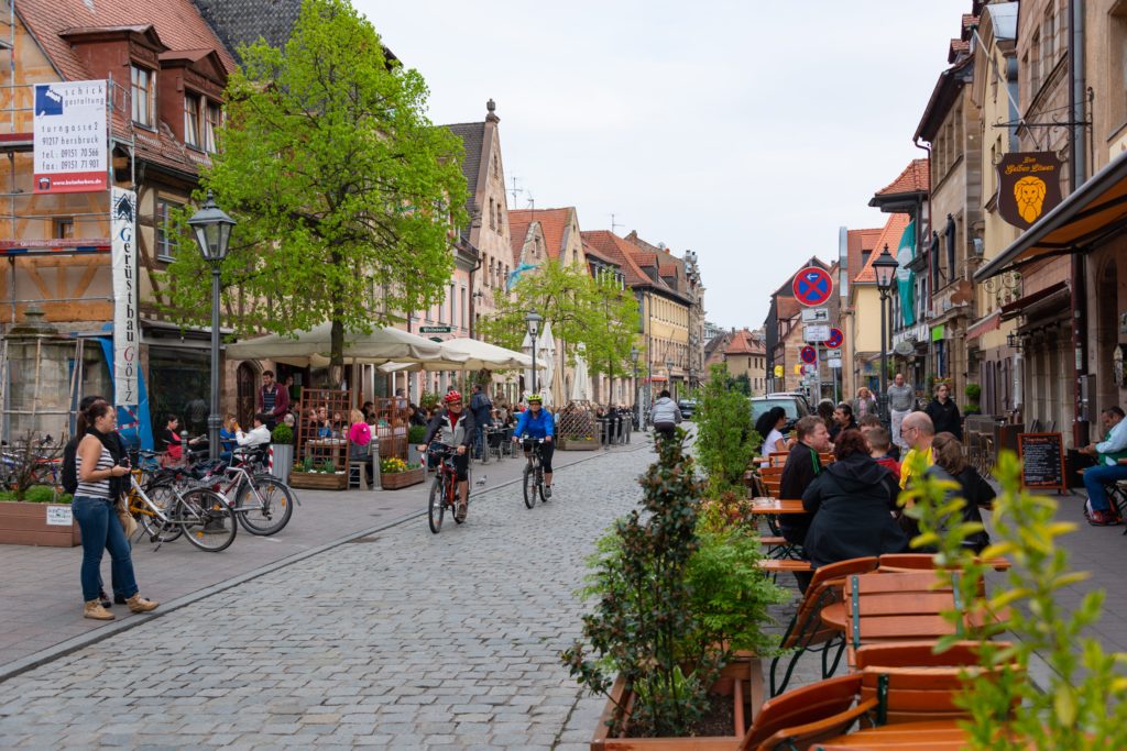 Featured in Best Destinations for Solo Travelers by Jaya Travel & Tours, this image shows a small town in Germany with Bavarian design and people in cafes.
