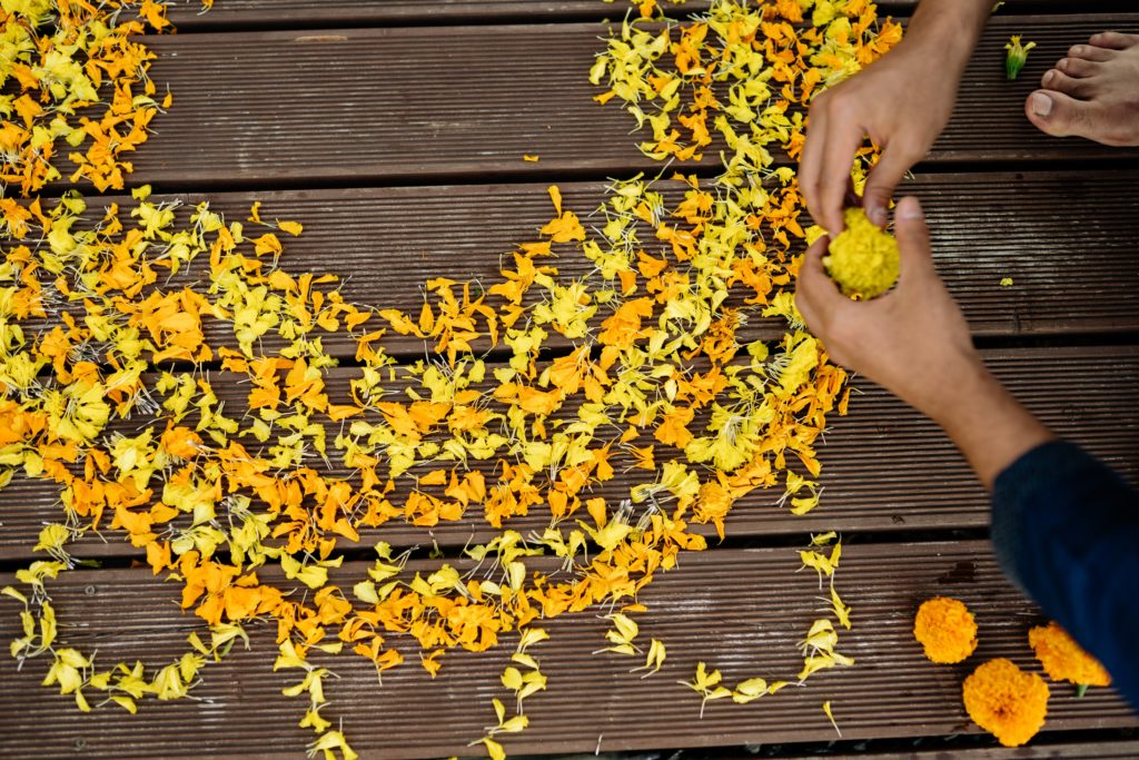 Featured in How to Celebrate Diwali in India by Jaya travel & Tours, this image shows hands making a yellow flower rangoli.