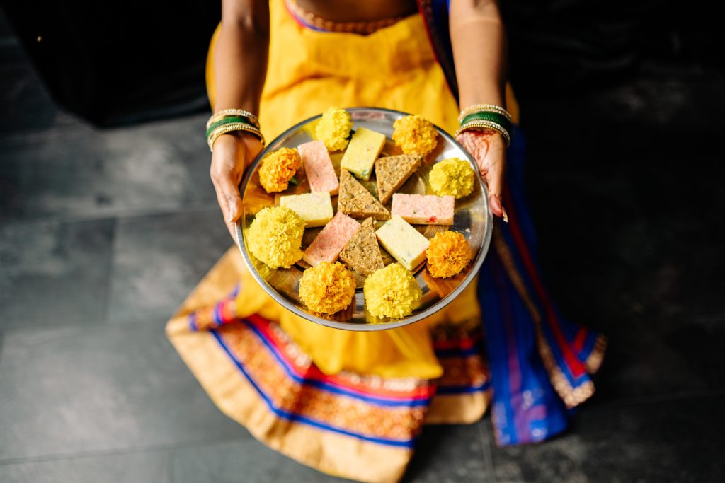 Featured in How To Celebrate Diwali In India by Jaya Travel & Tours, this image shows a woman holding out a tray of Indian sweets.