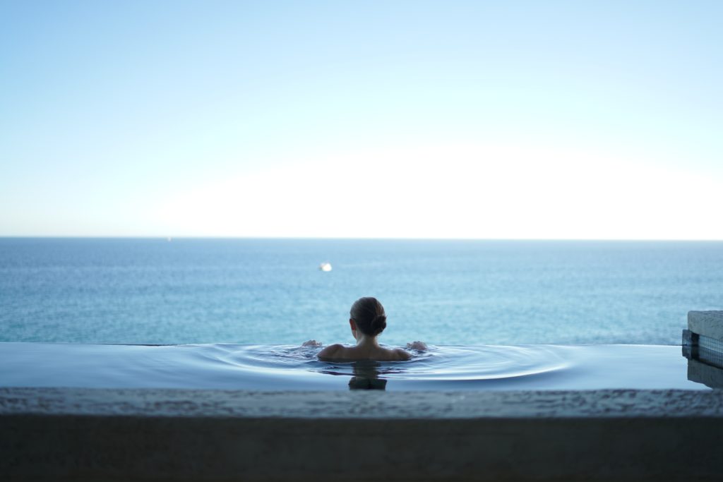 Featured in Winter Travel Destinations by Jaya Travel & Tours, this image shows a woman swimming in a pool looking at the skyline.