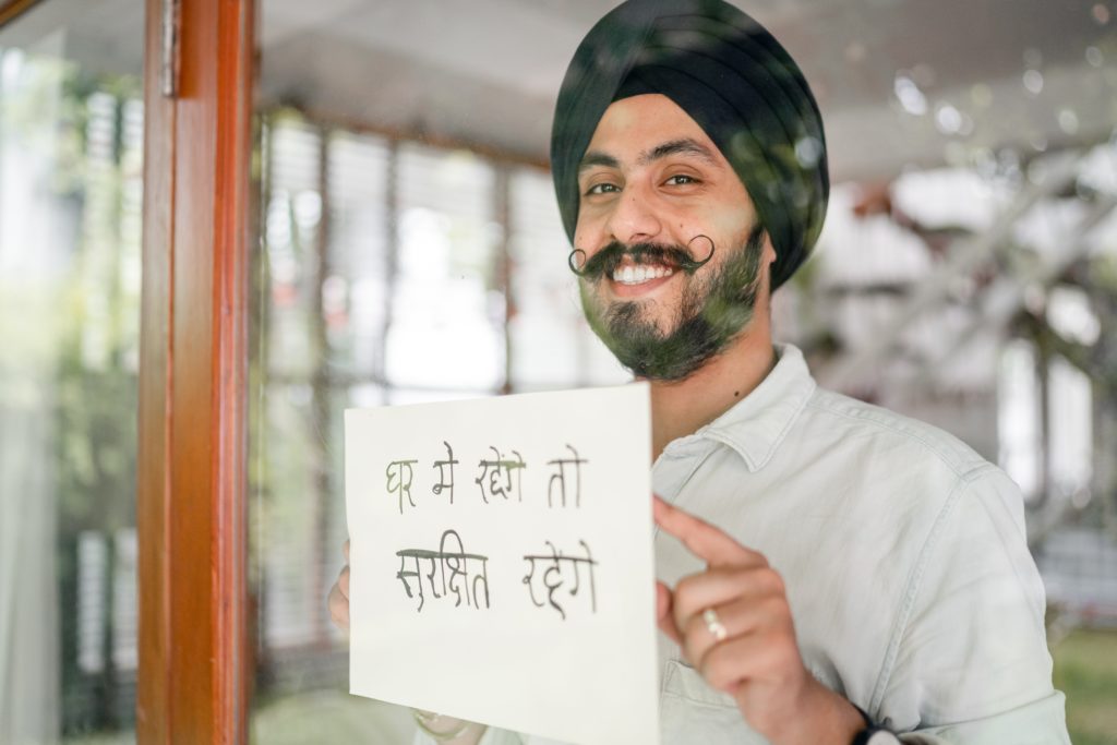 Featured in "Traveling with a Language BArrier" by Jaya Travel & Tours, this image shows a mean wearing a turban and holding up a sign in a foreign language.