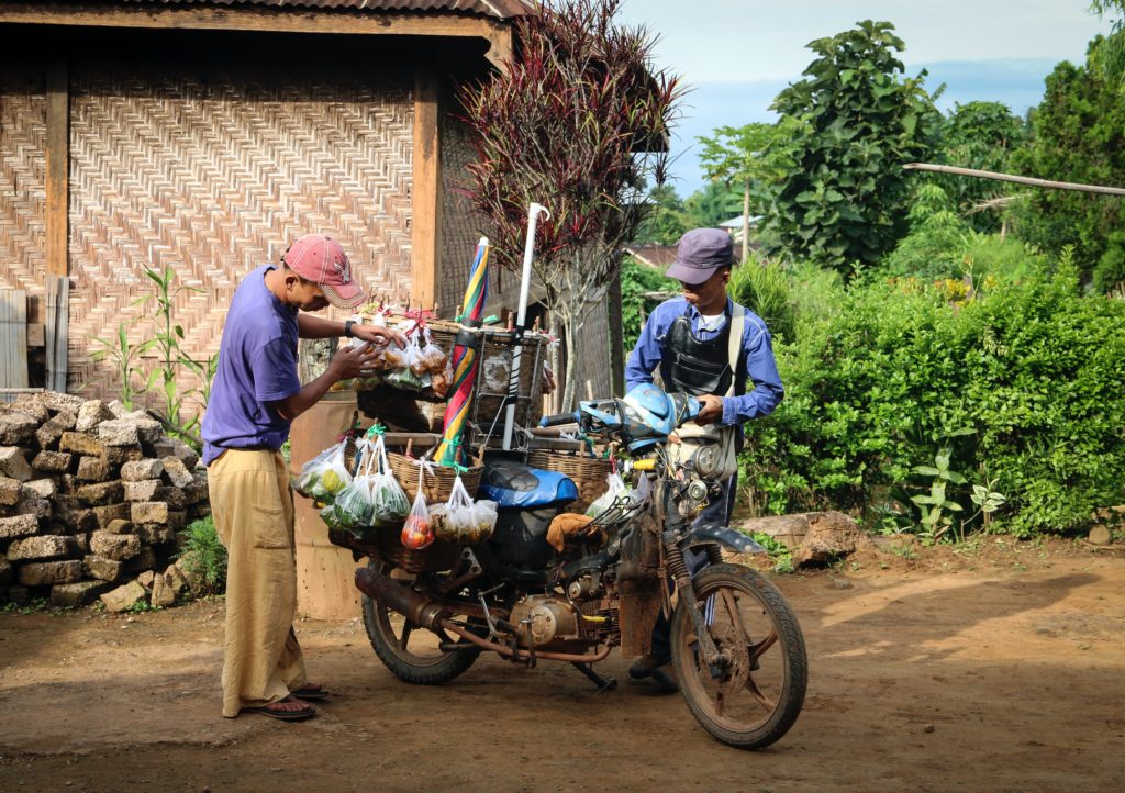 Featured in Responsible Travel Guide by Jaya Travel & Tours, this image shows a local man operating a food stand off a motorcycle.
