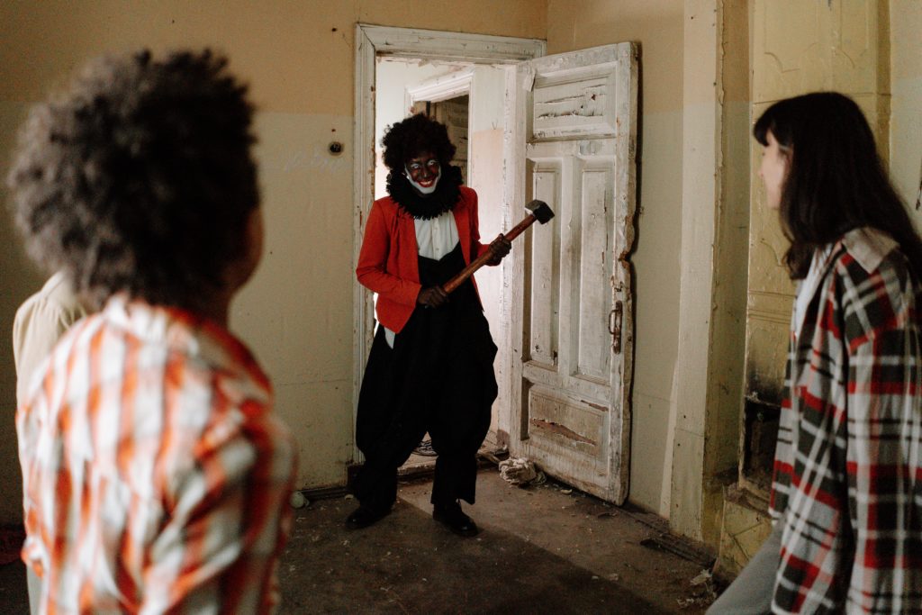 Clown attacking two women inside a house featured by Jaya Travel & Tours in the Halloween Destinations Around the World blog