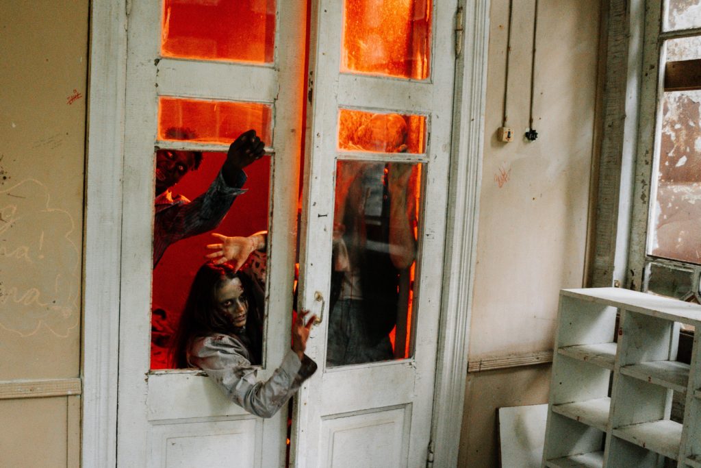 Zombies breaking through a window inside a house featured by Jaya Travel & Tours in the Halloween Destinations Around the World blog