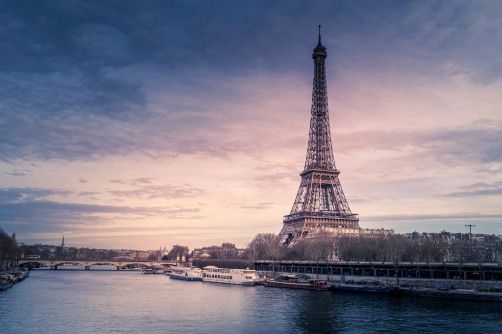 Featured in the Jaya Travel & Tours blog "Jaya's Best of Europe Tour," this image features a pink-purple sunset behind the iconic Eiffel Tower in France.