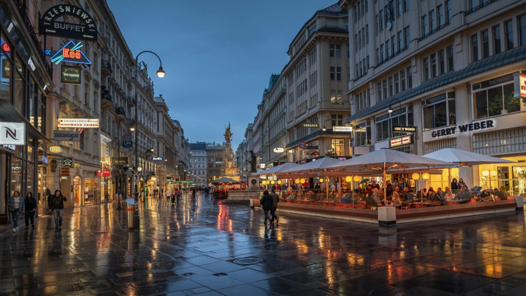 Featured in the Jaya Travel & Tours blog, "Jaya's Best of Europe Tour," this image shows a street in Vienna, Austria at night illuminated by the lights from stores.