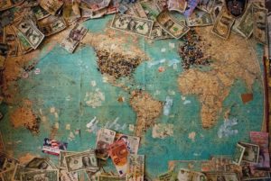 money spread over the world map from Jaya Travel & Tours blog "Save more with Jaya Travel agents"