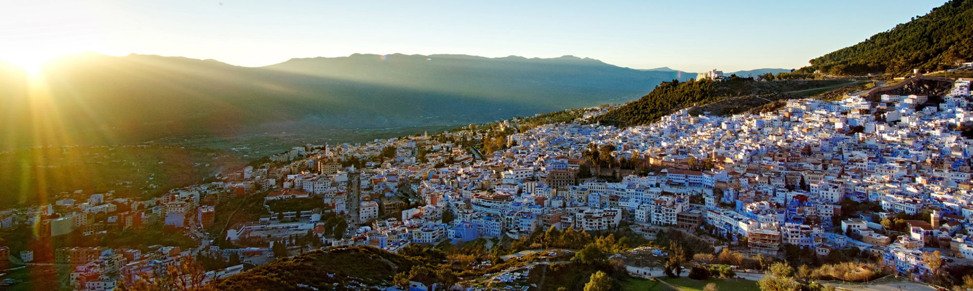 A panorama cityscape view of the blue city and Rif Mountains at sunset in Chefchaouen, Morocco with Jaya Travel & Tours.