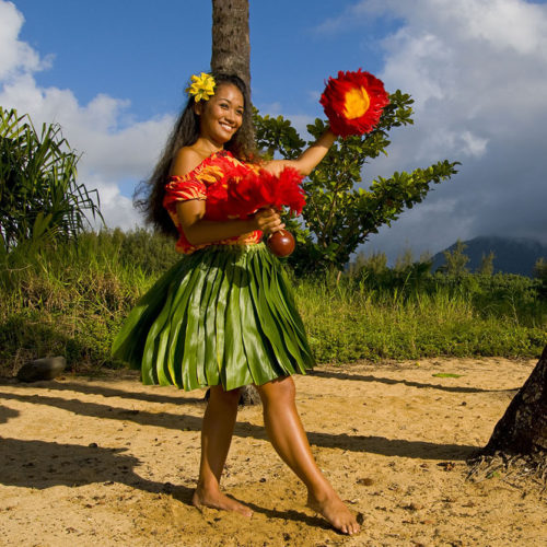 A native Hawaiian hula dancer performs on the beach in Kauai for travelers that booked one of Jaya's Travel Promotions on the luxurious Hawaii island hopping tour.