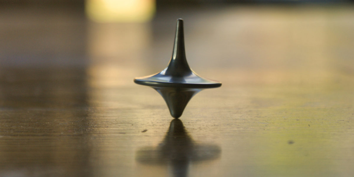 a metal spinner, like the one from the movie inception, spins on a wooden table symbolizing a dream.